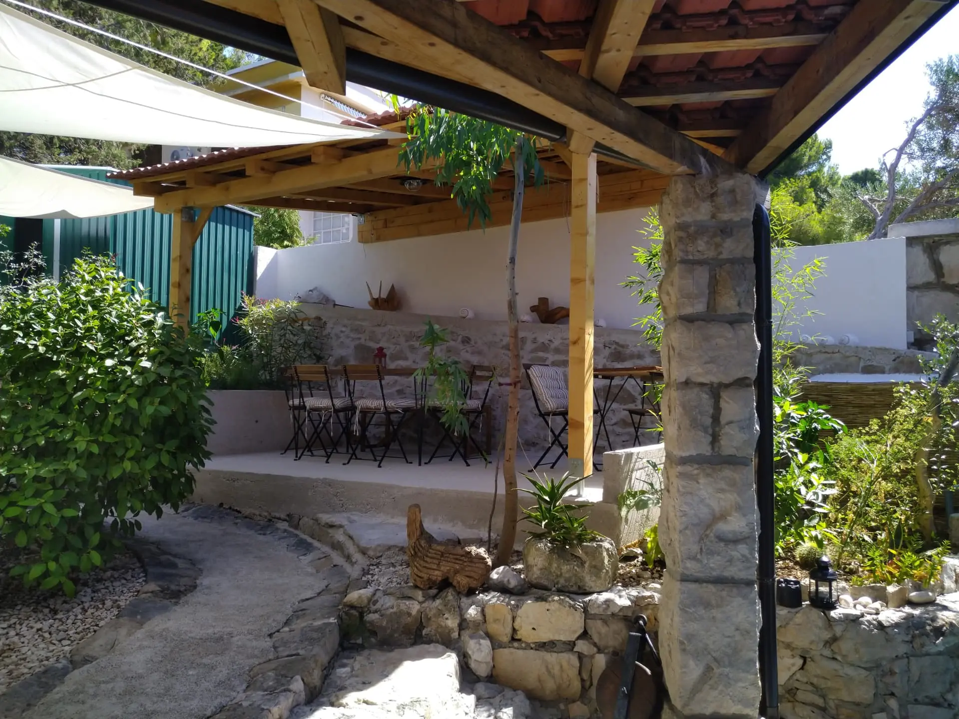 Shaded pergola seating area with stone columns and wooden beams for private VIP tables